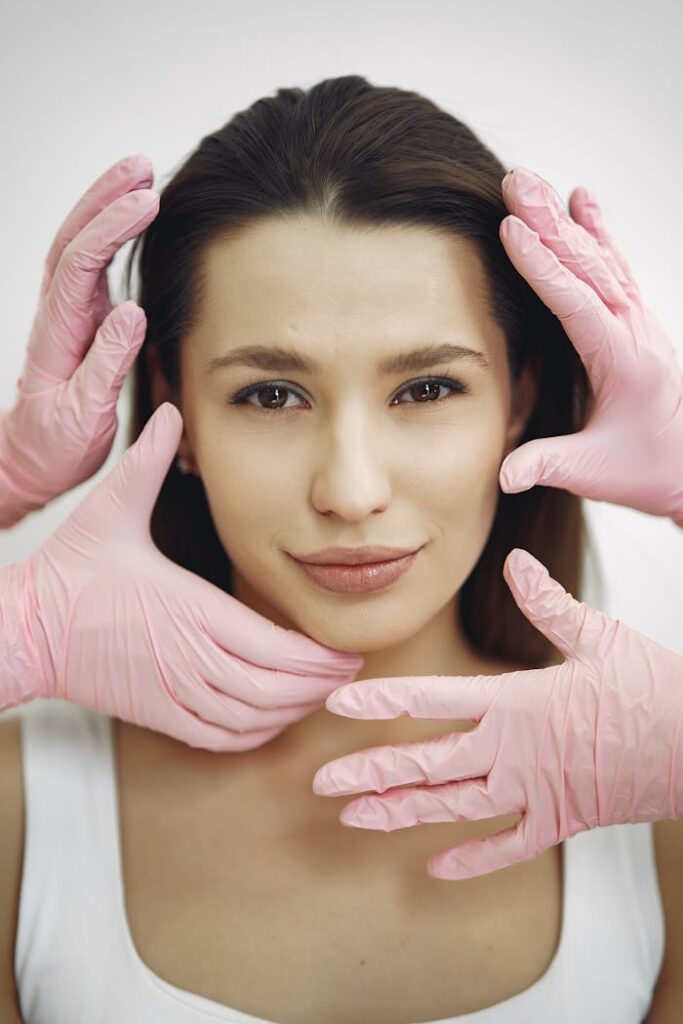 pexels-photo-3985314 Close-up of a woman receiving a skincare treatment with pink gloves indoors.